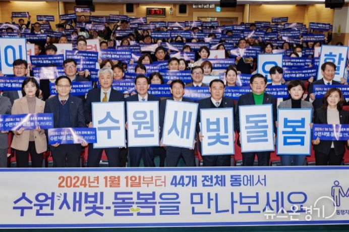 지난해 12월 수원시 관계자들이 수원새빛돌봄 전체 동 확대를 홍보하는 손팻말을 들어 보이고 있다.