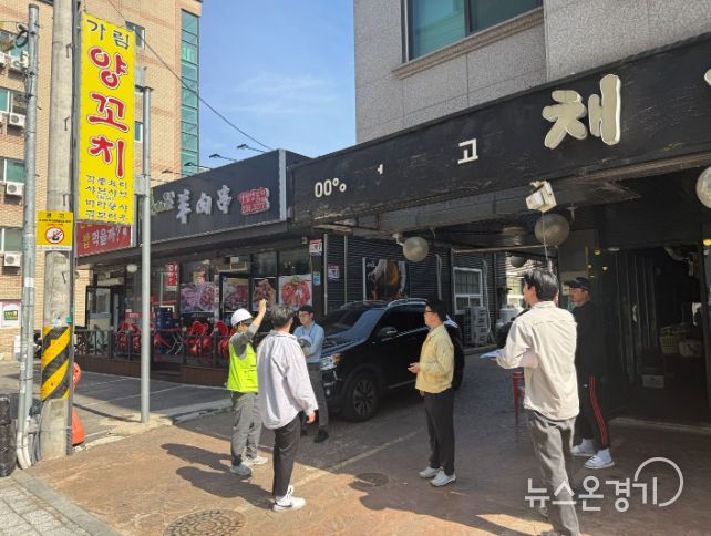 정명조 건축과장과 관계자들이 도로변 상가 간판의 안전 상태를 확인하며 현장점검을 하고 있다.